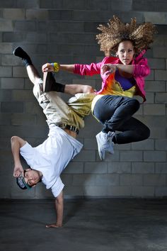 two people doing tricks in front of a brick wall