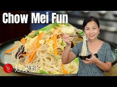 a woman holding a spoon in front of a plate of food with chopsticks