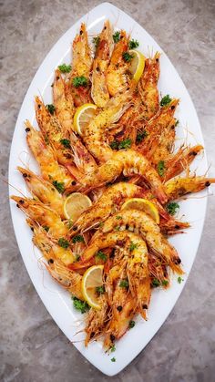 cooked shrimp with lemons and parsley on a white platter