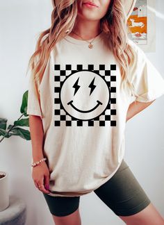 Checkered Pattern Smiley Face Oversized Vintage T-Shirt, Retro Smiley Face Shirt, Lightning Smiley Face Shirt, Smile Shirt, Comfort Colors This oversized Comfort Colors shirt is perfect for chill days, and the mineral wash gives it a rad vintage feel.  You'll love this tee's slouchy fit and cool design.  CARE INSTRUCTIONS Wash items inside cold water, do not bleach, dry clean, and iron directly on the design. Tumble dry low. PRODUCTION AND SHIPPING The standard production time is 1-3 business days. (We usually process and ship out the orders within two business days.) USA Orders: Standard: 2 to 6 days to get delivered (after processing time) Priority: 1 to 4 days to get delivered (after processing time) Express: 1 to 2 days to get delivered (after processing time)    If you need the item s Two Cool Shirt, Smiley Face Lightning Bolt Cake, Smiley Face Hat Outfit, Checkered T Shirt, Smile Face Shirt, Smiley Face 3rd Birthday, Smiley Shirt Design, Smiley Tshirt Design, Smiley Bday Theme