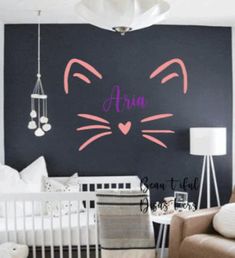 a baby's room with a black wall and pink cat decal on the wall