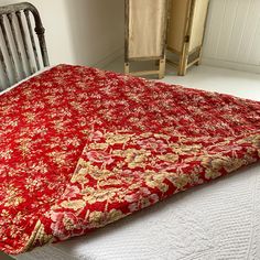 a bed with a red and gold bedspread on it