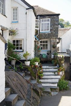 the stairs lead up to an old house with potted plants on each floor and windows