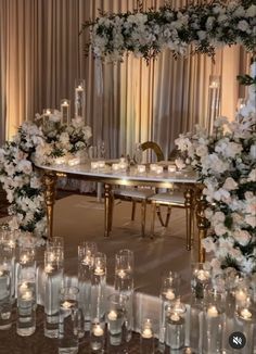 a table topped with lots of white flowers and candles