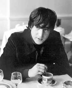 a man sitting at a table with cups and saucers