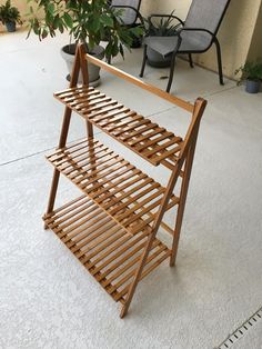 a wooden rack sitting on top of a white floor next to two chairs and a potted plant