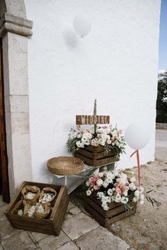 two wooden boxes filled with flowers next to a white building and balloons in the air