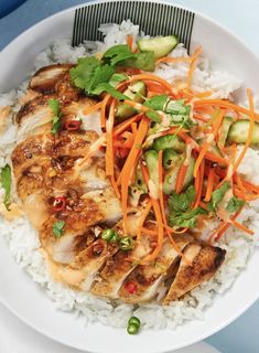 a white plate topped with rice and chicken covered in sauce, veggies and carrots