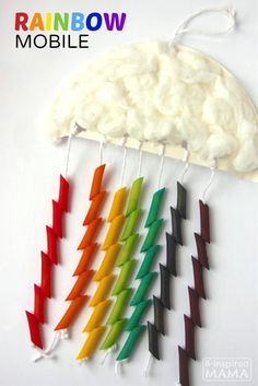 several different colored toothpicks are hanging on a white wall with clouds in the background