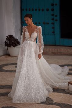 a woman in a white wedding dress with long sleeves and an open - back design