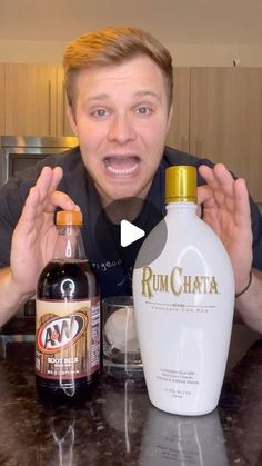 a man holding two bottles of rumchata on top of a kitchen counter next to an empty bottle