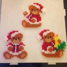 three cross stitch teddy bears sitting on top of a white mat with christmas decorations around them