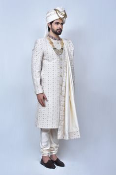 Cream sherwani with floral embroidered motifs and welt pocket in front. Comes with cream churidar and border embroidered dupatta.
Components: 3
Pattern: Embroidery
Type Of Work: Thread
Neckline: Mandarin Collar
Sleeve Type: Long
Fabric: Art Silk, Silk Blend
Color: Cream
Other Details: 
Welt pocket in front
Slits on the sides
Closure: Button front
Note: The mala and safa worn by the model is not for sale
Occasion: Groom - Aza Fashions Unstitched Off White Naqshi Bandhgala, Ceremonial Off White Sherwani For Eid, Off White Traditional Bandhgala With Drape, Traditional Cream Unstitched Suit With Naqshi Details, Traditional Designer Sherwani With Cutdana, Traditional Sherwani With Cutdana For Designer Wear, Designer Raw Silk Sherwani With Dabka, Off White Dabka Sherwani For Transitional Season, Designer Cream Bandhgala With Cutdana