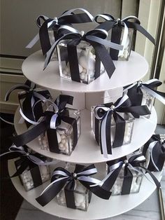 three tiered cake with black and white ribbons on it's sides, each holding small cubes filled with candies