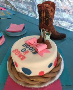 a birthday cake with cowboy boots on top and polka dots around the edges, sitting on a blue tablecloth