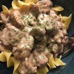 a blue plate topped with pasta and meat covered in gravy