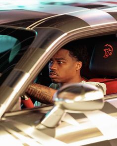 a man sitting in the driver's seat of a car with tattoos on his arm