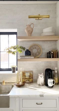 a white kitchen with open shelving above the sink