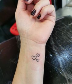 a woman's wrist tattoo with two hearts on the left side of her arm