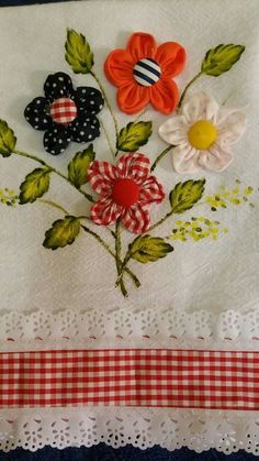 some flowers are sitting on top of a piece of white cloth with red and blue trim