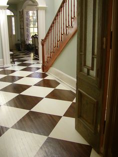 an open door leading to a hallway with white and brown checkerboard flooring