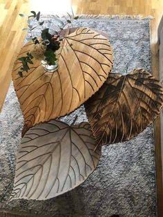 three wooden leaf shaped tables sitting on top of a rug