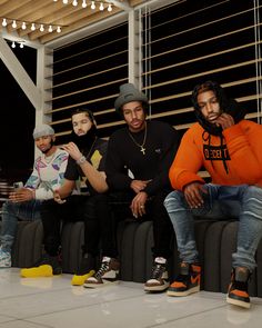 four young men sitting on top of a couch next to each other