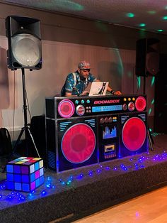 a man sitting on top of a boombox in front of some speakers and lights