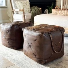 two brown leather storage bags sitting on top of a white rug in front of a fireplace