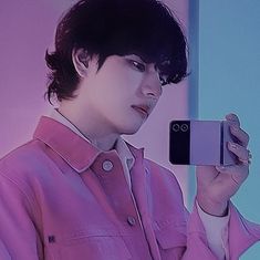 a woman taking a selfie with her cell phone in front of her, wearing a pink shirt and white collared shirt