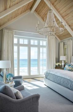 a bedroom with a large bed sitting under a chandelier next to a window