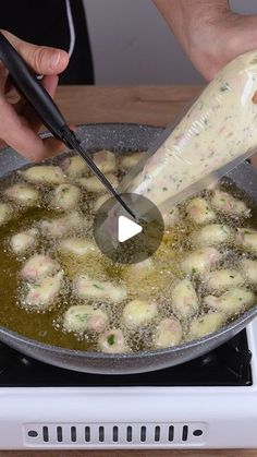 someone is cooking dumplings in a pan on top of the stove with a spatula