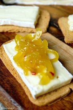 crackers with cheese and jelly on them sitting on a cutting board