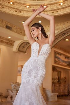 a woman in a white wedding dress is posing for the camera with her arms up