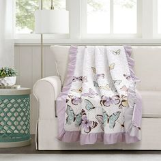 a white couch sitting next to a window covered in a purple and white butterfly blanket