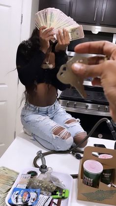 a woman sitting on the kitchen counter holding cash