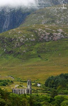 an old church sits in the middle of a valley surrounded by green trees and mountains