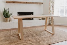 a wooden table sitting on top of a rug in front of a fire place with potted plants