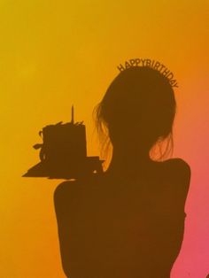 the silhouette of a woman with a birthday cake in her hand, against an orange and yellow background