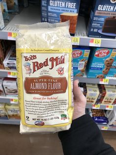 a person holding up a bag of almond flour in a store aisle with other items on the shelves