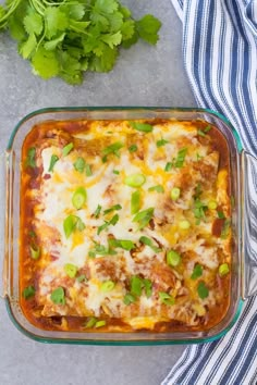 a casserole dish with meat, cheese and green onions in it next to cilantro