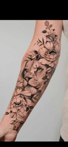 a woman's arm with flowers on it and a lion in the middle, surrounded by roses