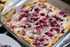 a casserole dish with cranberry sauce and cheese on top, next to crackers