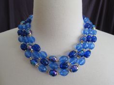 "This necklace is a stunning piece.  Lovely light blue oval faceted beads mixed with dark blue aurora borealis faceted beads, tiny round gold spacer beads and gold findings put together to create a lovely blue sensation of color.  This necklace is absolutely beautiful.  It catches the light and just sparkles away.  The contrast of the light and dark blue create a beautiful visual.  The dark blue with the aurora borealis almost look like fish scales as they shimmer with the light.  They are in ex Blue Oval Faceted Bead Jewelry, Blue Faceted Oval Beads Jewelry, Blue Faceted Round Bead Necklaces, Blue Faceted Necklaces With Round Beads, Blue Necklaces With Faceted Round Beads, Blue Double Strand Faceted Bead Jewelry, Blue Faceted Beads Double Strand Jewelry, Blue Costume Jewelry Beaded Necklace With Faceted Beads, Blue Faceted Beads Crystal Necklaces