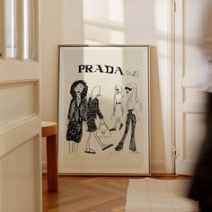 a framed fashion poster on the floor in front of a door with an advertisement for prada