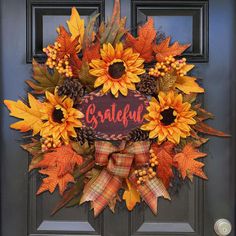 a wreath with sunflowers, leaves and berries on the front door to celebrate fall