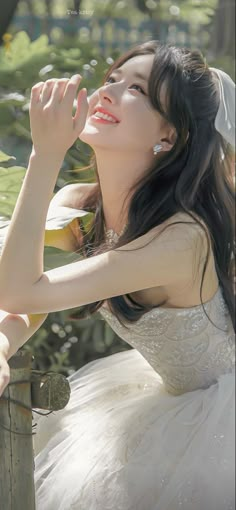 a woman in a white dress is leaning on a fence and looking up at the sky