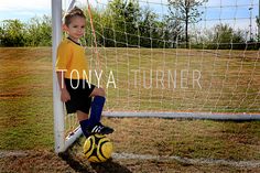 a young boy standing in front of a soccer goal wearing a yellow shirt and black shorts