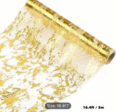 a roll of gold foil with white and gold glitter on it's side, next to a ruler