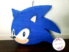 a paper mache sonic the hedgehog mask on a wooden table with a white wall in the background